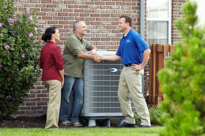 A King technician shaking hands with homeowners beside a new AC