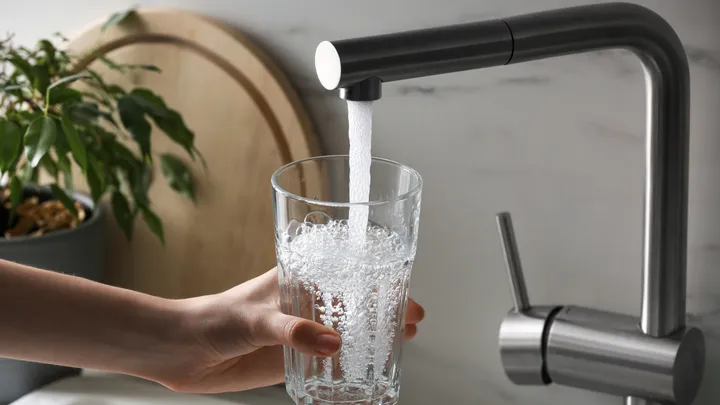 Glass being filled with tap water from a kitchen faucet