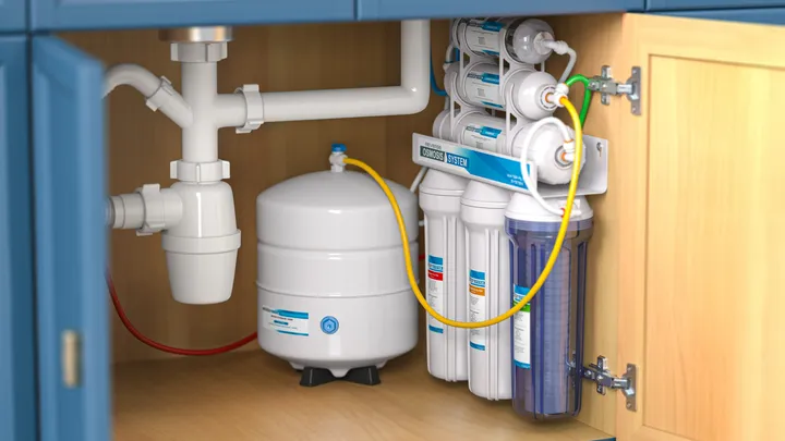 Under-sink reverse osmosis water filtration system with storage tank installed in a kitchen cabinet