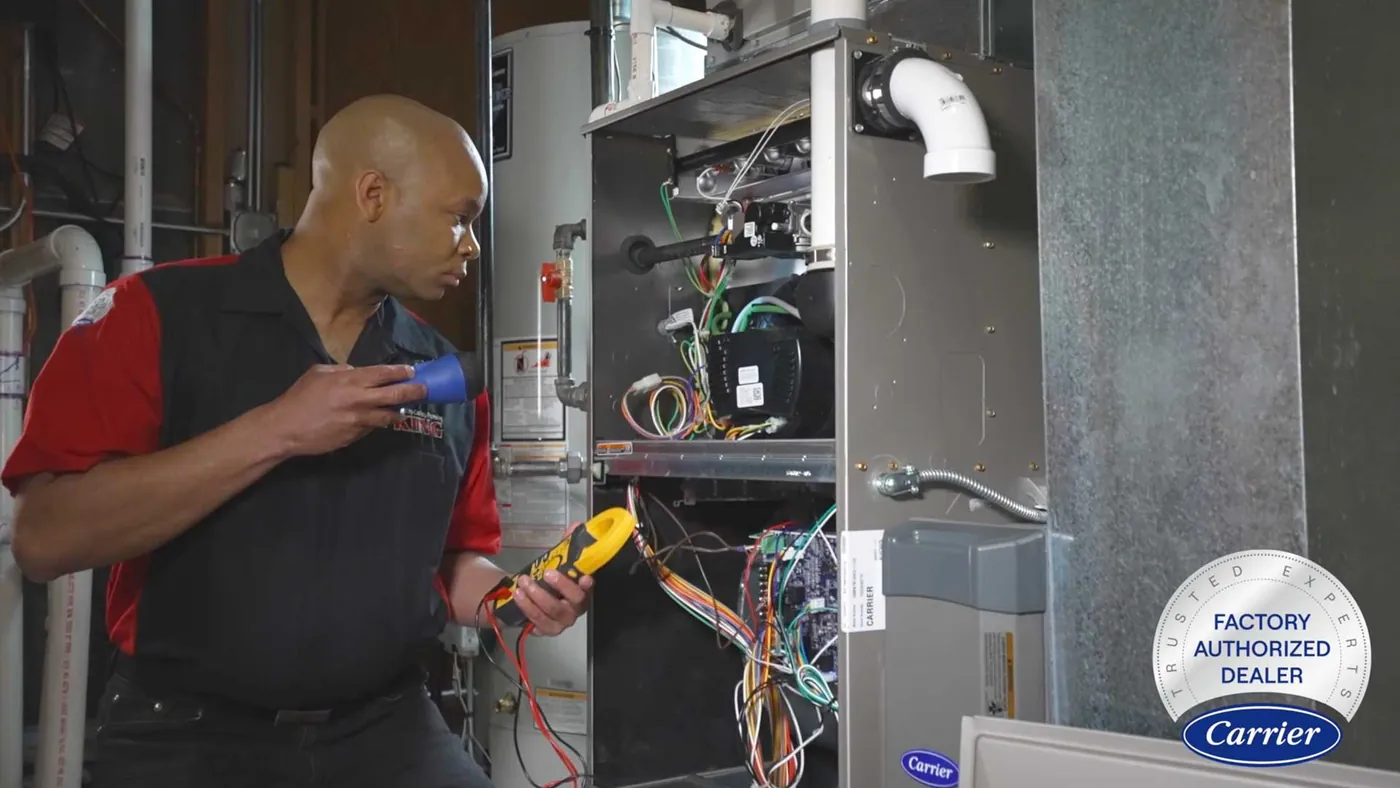 A King technician testing a Carrier furnace with the Carrier Factory Authorized Dealer seal