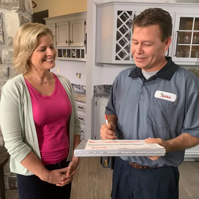 A King technician reviewing a maintenance plan with a homeowner in her kitchen