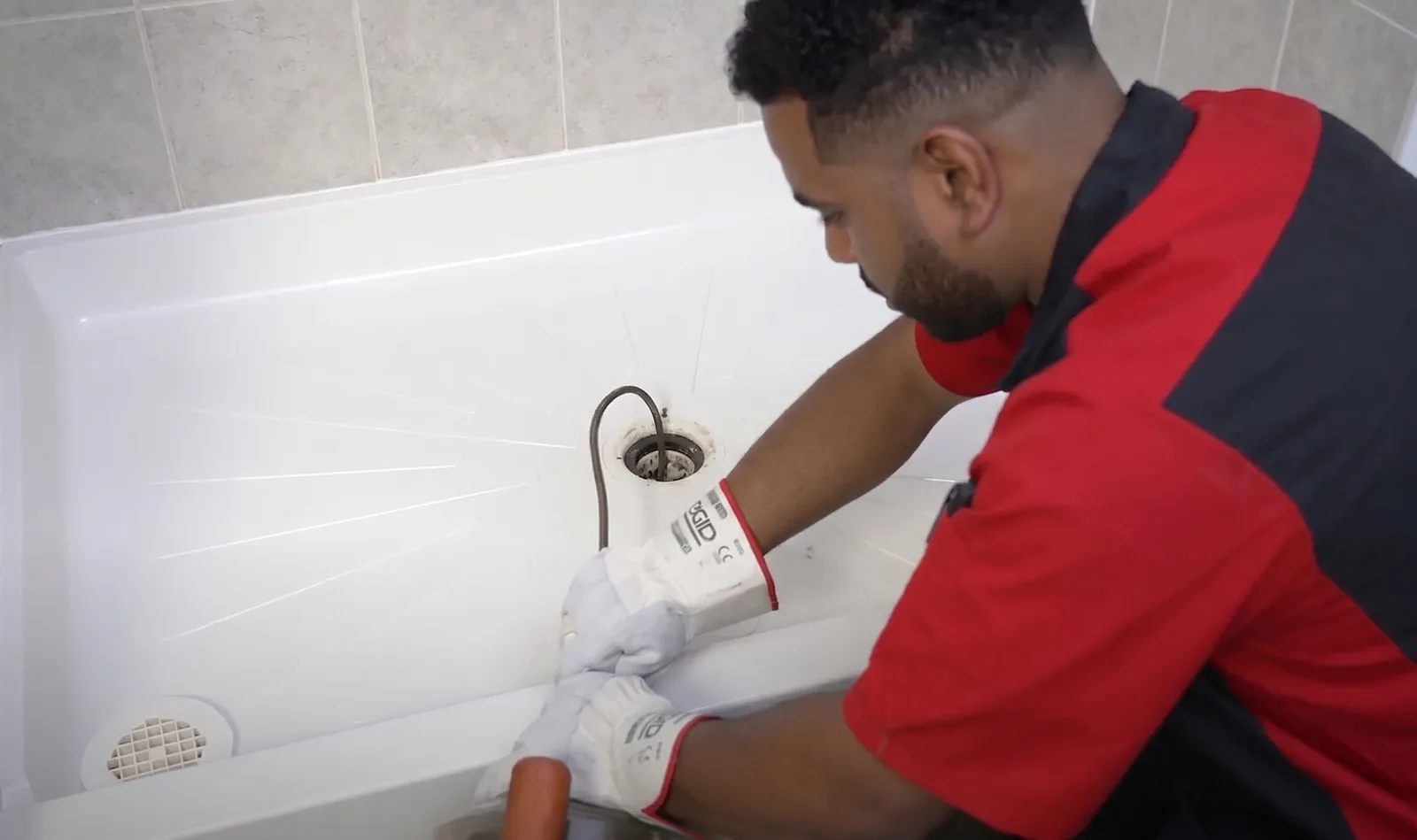 A King plumber clearing a shower drain
