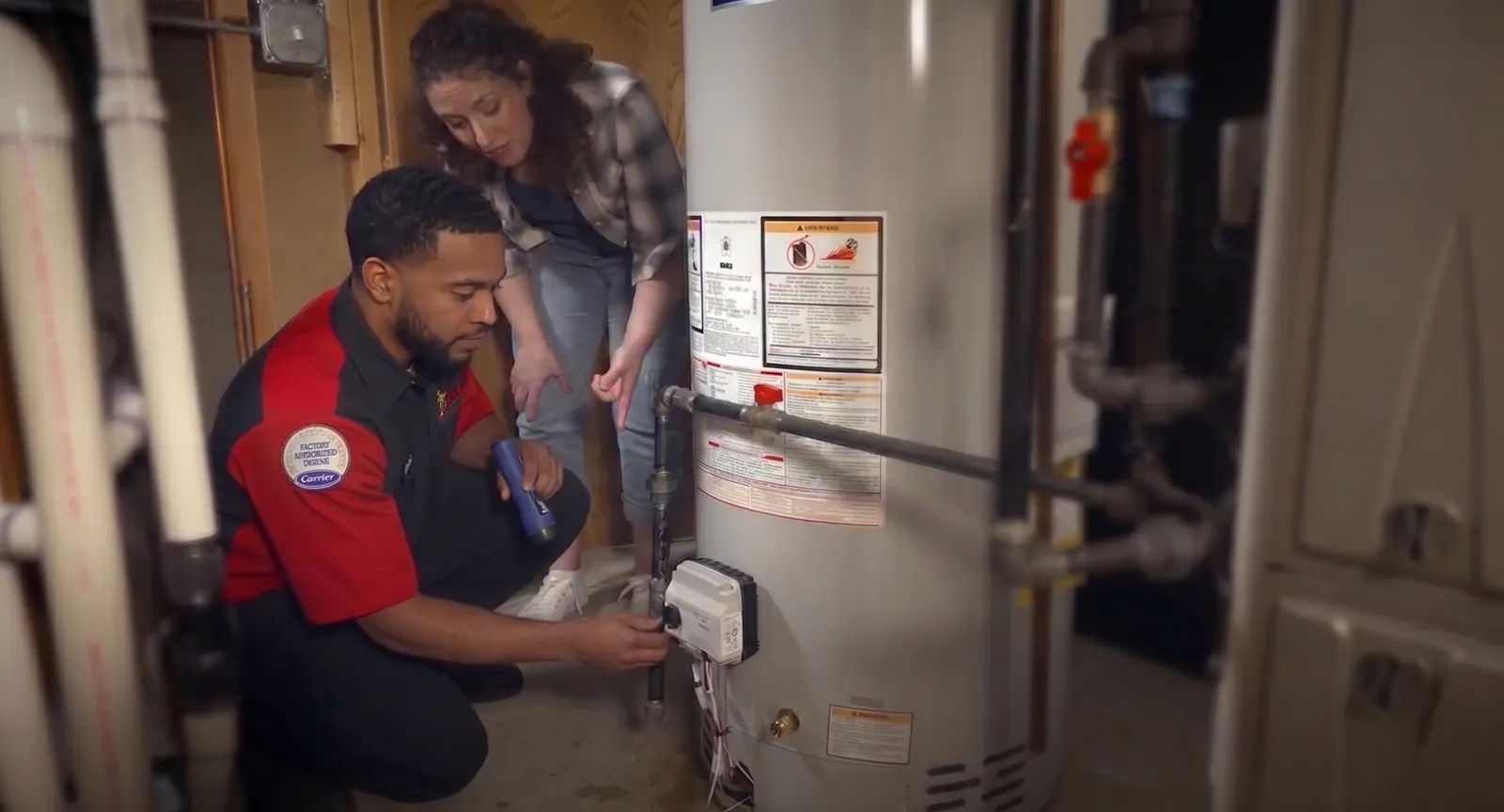 A King plumber checking a water heater with a homeowner