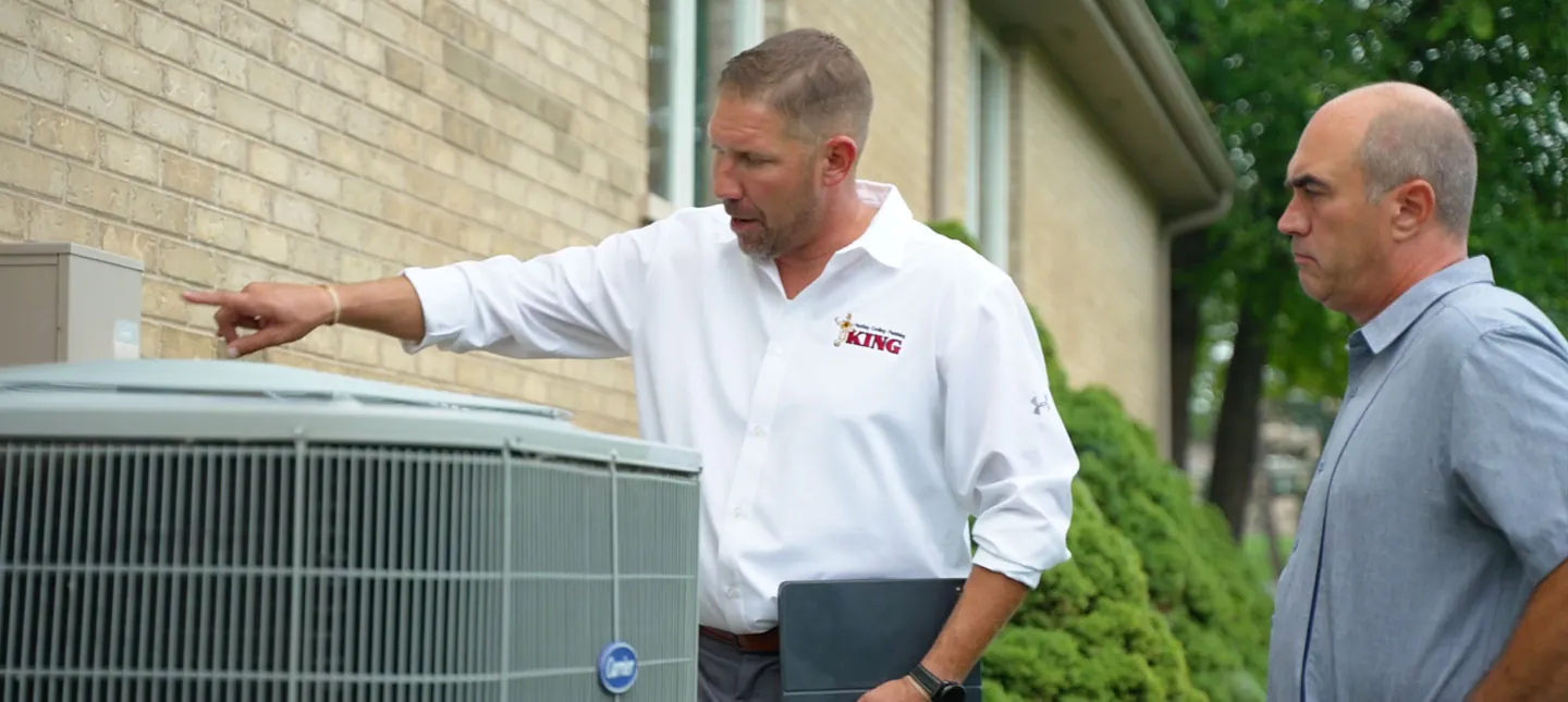 A King HVAC technician walks a homeowner through their outdoor air conditioning unit