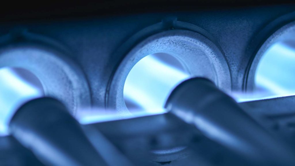 The natural gas burners of this furnace ignite, generating heat energy that will be distributed throughout the home.