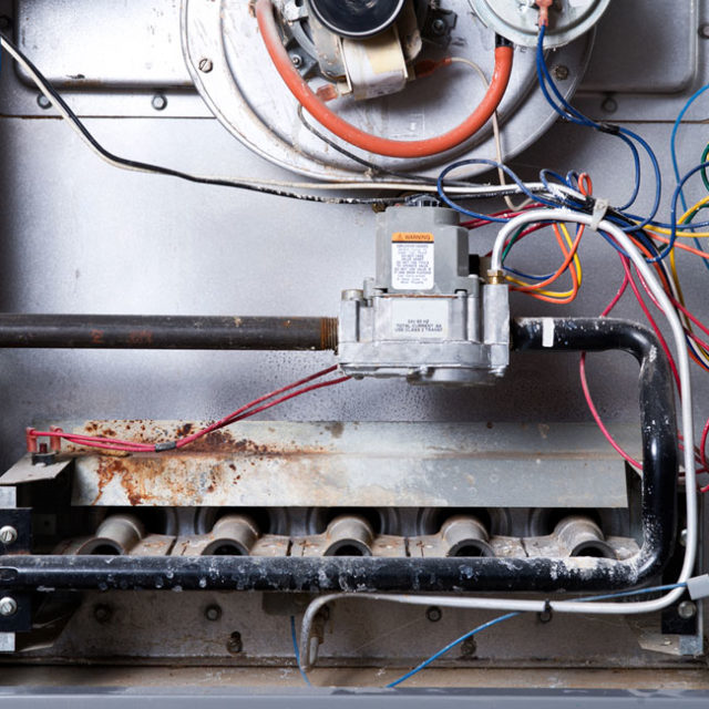 As part of our heating maintenance service in Chicago, our technicians clean out the inside of dirty furnaces like this one.
